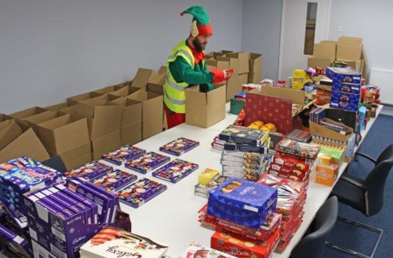 •	Helper Marc, from Polyroof, dressed as an elf while he helps pack the cheer boxes