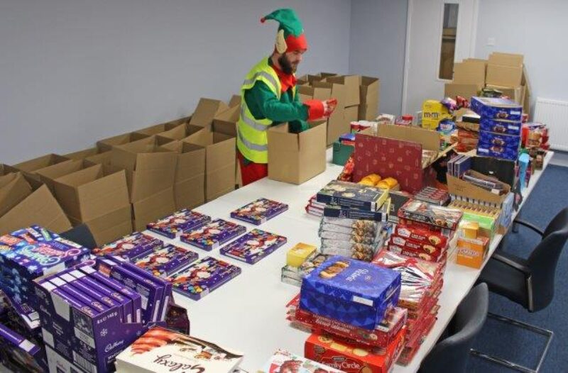 •	Helper Marc, from Polyroof, dressed as an elf while he helps pack the cheer boxes